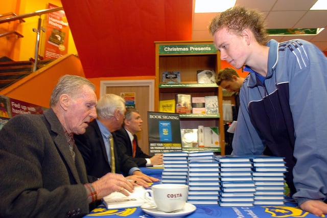 Roger Holmes launched his book Portsmouth FC Miscellany at Waterstone's in Commercial Road in November 2006 and a handful of ex-Pompey players were on hand to sign copies - Len Phillips signs a copy of the book for 14-year-old Tom Dubber (065114-139)
