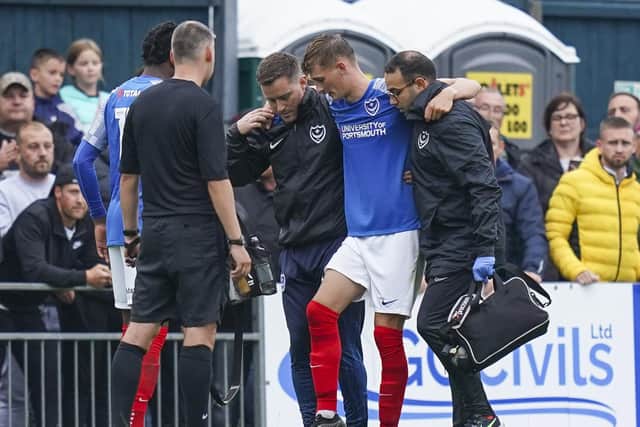Temporary Pompey physio Paul Cremin (left) helps Josh Dockerill leave the pitch after his second-half injury on Friday night. Picture: Jason Brown/ProSportsImages