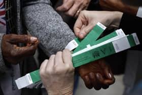 People put on the wristbands that indicate their place in line along Shad Thames while waiting in line to pay their respects to Queen Elizabeth II as she lies in state at Westminster Hall. Picture:  Chip Somodevilla/Getty Images.