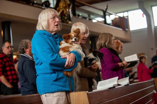 Members of the St George's Church congregation hold their dogs while they sing hymns at a previous Blessing of the Animals service. Picture: Vernon Nash (051019-024)