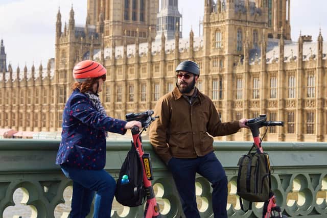 A man and woman with Voi scooters on Westminster Bridge