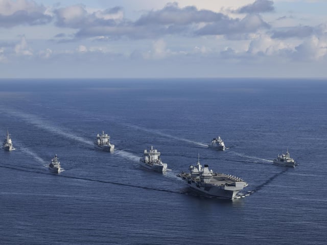 The UK CARRIER STRIKE GROUP during Exercise Joint Warrior. Aerial imagery of the UKCSG Task Group taken from a Merlin Mk2 of 814 Naval Air Squadron.Viewed from the front - HMS Prince of Wales; Row 2 (L-R) – HMS Portland, RFA Tidesurge, HMCS Charlottetown; Row 3 (L-R) – SNS Cristόbal Colόn, RFA Tidespring, HMDS Niels Juel.