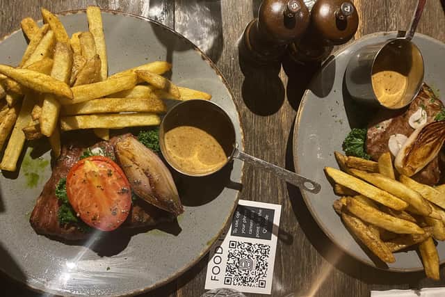 The flat-iron steaks, served with chips, kale, roasted shallots, pickled garlic, plum tomato and herb oil.