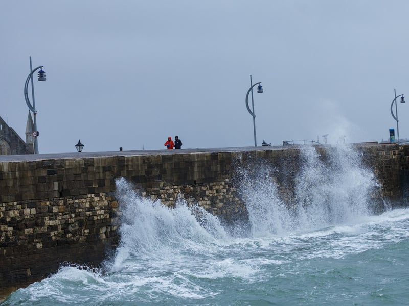 A moody sea crashed waves high onto footpaths as passer-by's did their best to get out the way