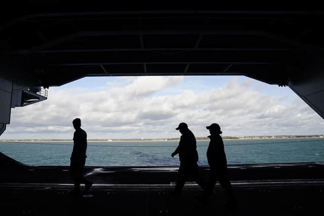 Crew members are silhouetted as they walk in the hanger on board the USS Gerald R. Ford, the 'world's largest warship', during a media visit while it is anchored in the Solent during a stopover in Portsmouth on its maiden deployment. Picture: Andrew Matthews/PA Wire