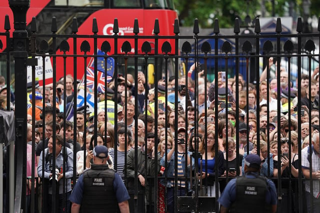Members of the public stand outside the gates of Downing Street as Prime Minister Boris Johnson reads a statement outside 10 Downing Street,