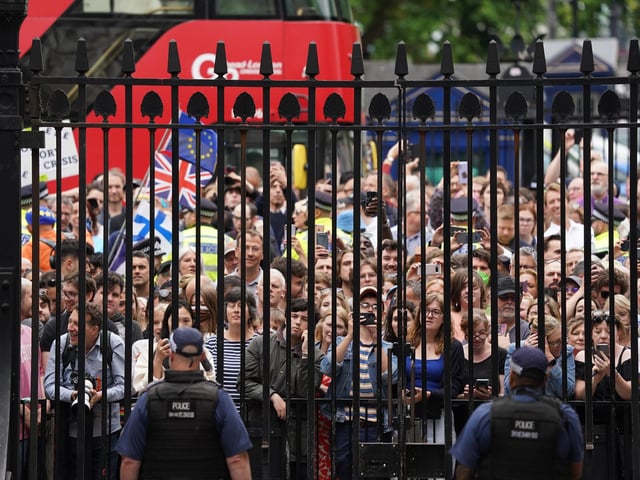 Members of the public stand outside the gates of Downing Street as Prime Minister Boris Johnson reads a statement outside 10 Downing Street,