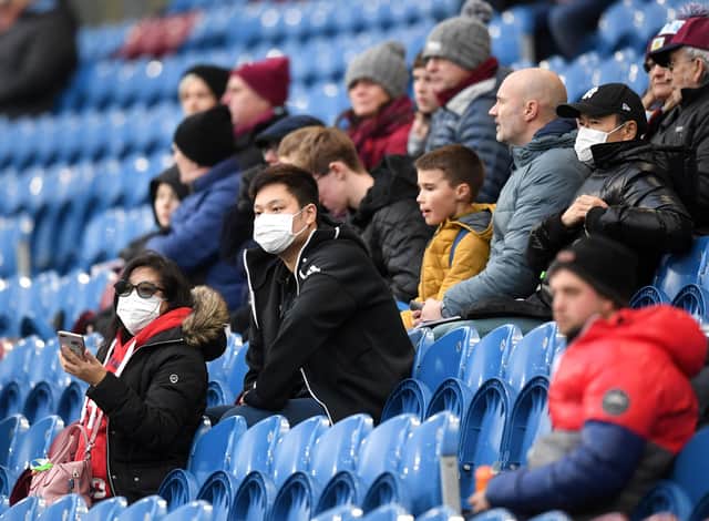 Fans wear disposable face masks prior to the Premier League match between Burnley FC and Tottenham Hotspur at Turf Moor.