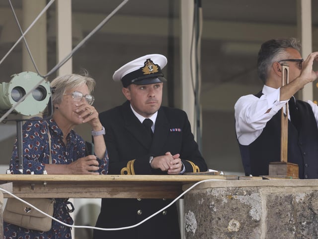 Pictured: Officers and dignitaries watch on as HMS Queen Elizabeth enters the Solent off of Cowes and conducts a gun salute in front of the Royal Yacht Squadron.