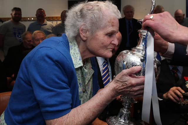 Joyce Tynan, who attended her first game in 1946, kisses a trophy. Picture: Chris Moorhouse