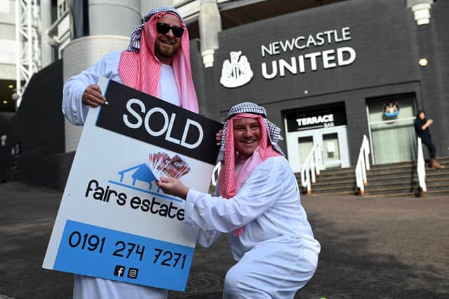 Newcastle United supporters dressed in robes pose with 'sold' placards as they celebrate the sale of the club to a Saudi-led consortium, outside the club's stadium at St James' Park, on October 8, 2021.
Photo by Oli Scarff/AFP via Getty Images