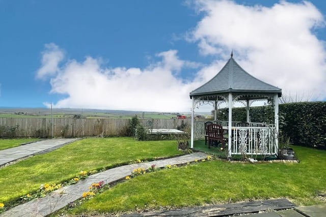 A pergola, paved seating areas and countryside views are features of the garden.