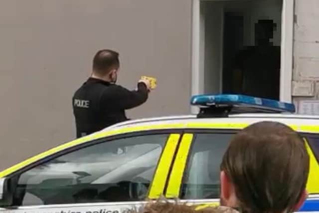A bypasser watches the drama unfold in North End moments before a police officer fired a Taser at a man.