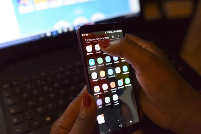 A woman using a smartphone in front of a laptop. Picture: ISSOUF SANOGO/AFP via Getty Images.