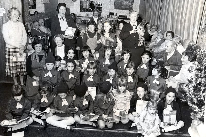 Brownies from the pack at St Margaret's Church, Eastney, Portsmouth, entertain residents at St Vincent's Lodge in December 1984. Brown owl Betty Webster is holding the cat.