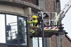 Southsea firefighter Max Hewett rescues a pigeon trapped by netting around the Knight and Lee building near Palmerston Road.