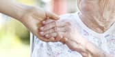 A woman holding hands with a carer.