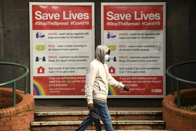 A man wearing a protective face mask passes a board displaying information how to restrict the spread of coronavirus Picture: Oli Scarff/AFP via Getty Images