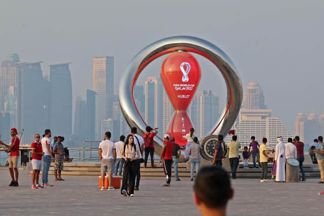 A picture taken on October 20, 2022, shows people walking past the Qatar 2022 FIFA World Cup countdown clock as it nears marking thirty days, in the Qatari capital Doha. Picture: KARIM JAAFAR/AFP via Getty Images.