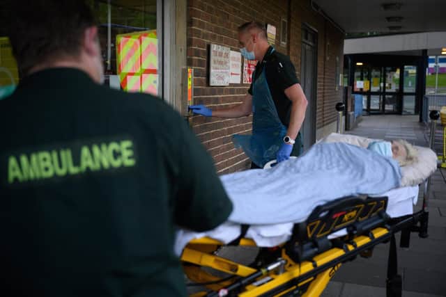 An ambulance crew wearing protective clothing transfer a patient, whose condition was described as not being related to Covid-19, from their ambulance to the Queen Alexandra hospital. Photo by Leon Neal - Pool/Getty Images)