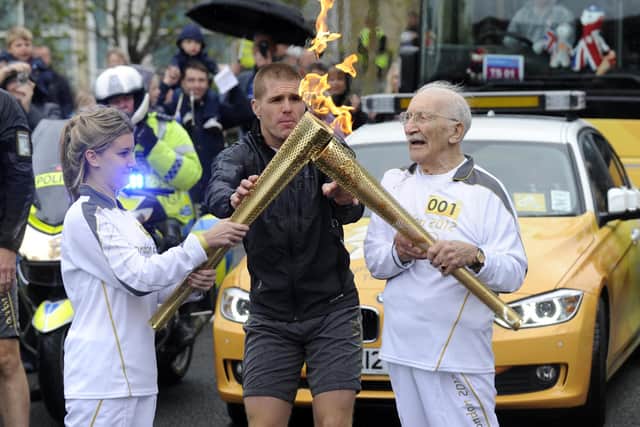 Portsmouth D-Day veteran John Jenkins passes the flame to April Hornsey during the Olympic Torch relay from Fratton Park in 2012
Picture: Ian Hargreaves  (122403-2)