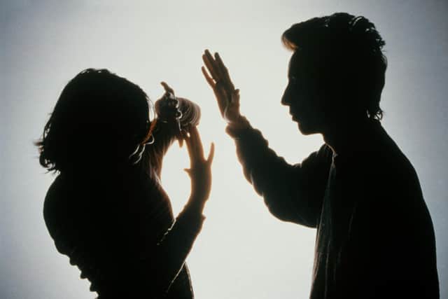 Silhouette of a woman protecting herself from a blow from her partner by holding her arms in front of her face.
