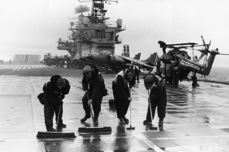 Four men scrubbing the 7000ft long flight deck on HMS Hermes during the Falklands conflict, May 1982.