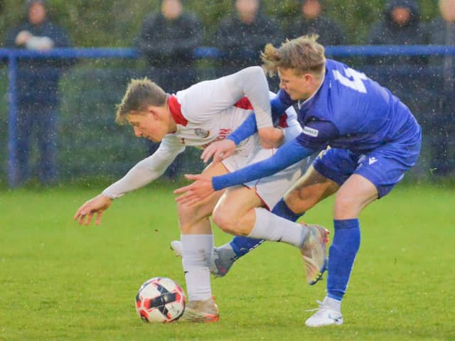 Horndean goalscorer Zack Willett, left, holds off a Baffins opponent in the rain. Picture by Martyn White