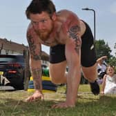 Dan Fallon tackling an epic marathon crawling and carrying a 45kg weight in his garden. Here he is pictured completing a bear crawl.