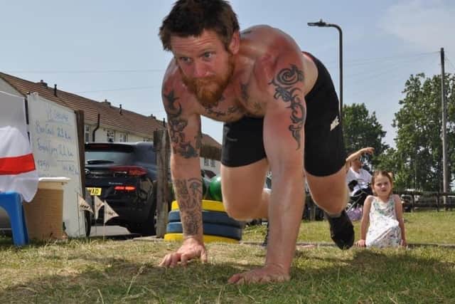 Dan Fallon tackling an epic marathon crawling and carrying a 45kg weight in his garden. Here he is pictured completing a bear crawl.
