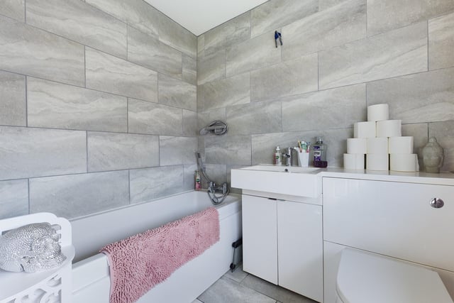 The bathroom is bright and modern, with a white bathroom suite, a shower over bath and grey floor and wall tiles, according to the estate agent.