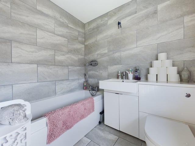 The bathroom is bright and modern, with a white bathroom suite, a shower over bath and grey floor and wall tiles, according to the estate agent.
