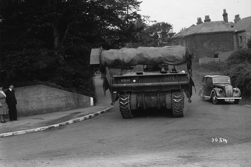 A Sherman 'Crab' mine-clearing flail tank, making its way to the coast to embark. The large drum on the front has chains attached to it, which would be spun round to set off landmines and clear minefields; it is all covered up. Note the white stripes on the curb because of the blackout.