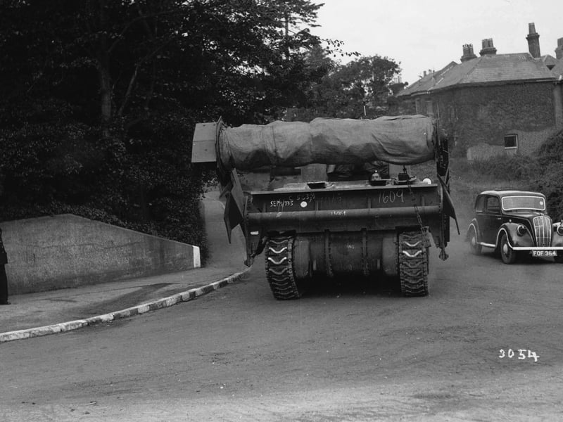 A Sherman 'Crab' mine-clearing flail tank, making its way to the coast to embark. The large drum on the front has chains attached to it, which would be spun round to set off landmines and clear minefields; it is all covered up. Note the white stripes on the curb because of the blackout.