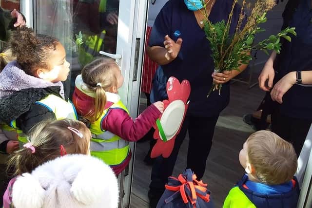 Nursery children present the bouquet to care home staff. 