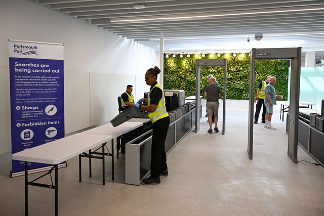 Staff work with the first passengers to arrive at the new terminal in the customs security baggage search area