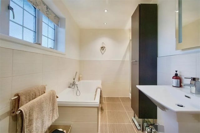 Modern four-piece suite comprising WC, panelled bath and an inset shower enclosure.