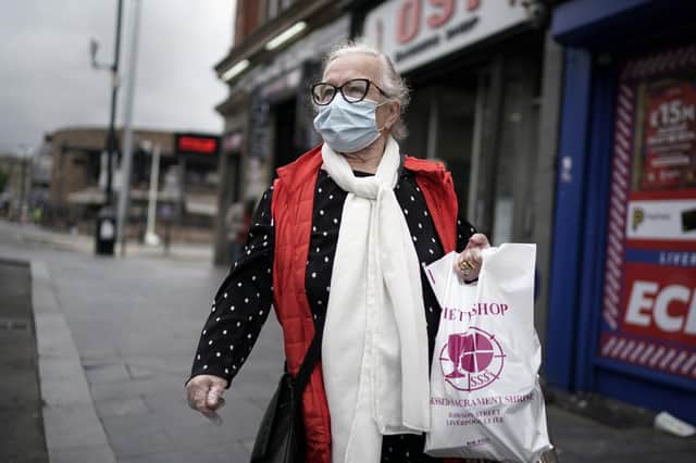 A woman wears a face masks carrying shopping bags on July 14, 2020 in Liverpool, United Kingdom. Photo by Christopher Furlong/Getty Images.