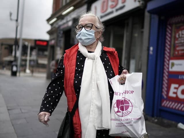 A woman wears a face masks carrying shopping bags on July 14, 2020 in Liverpool, United Kingdom. Photo by Christopher Furlong/Getty Images.