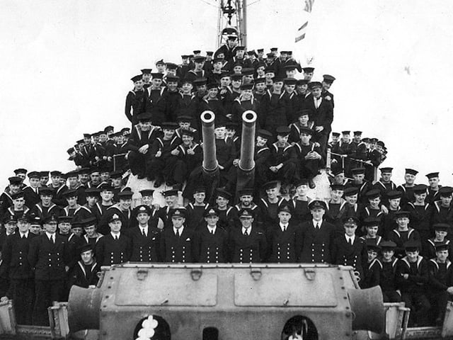 Crew member of HMS Lapwing. Here we see the officers and men of the ship gathered around A & B turrets.