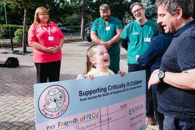Everlynn Hunt, eight, gifting the £10,000 cheque from Royale Life to the Friends of PICU