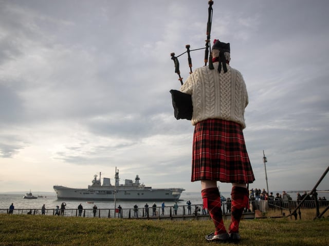 Piper Larry Cunningham plays his bagpipes as Britain's last serving aircraft carrier HMS Illustrious is towed from her home port at Portsmouth after being sold for scrap on December 7, 2016 in Portsmouth,. Photo by Matt Cardy/Getty Images