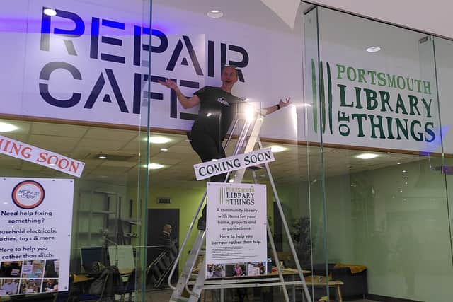 Volunteer Geoff Long at the new hub in Cascades Shopping Centre. The signs were built by another volunteer, Alice Kristina Rose.