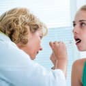 Doctor checking with depressor sore throat to teenage girl. Picture: Adobe Stock.