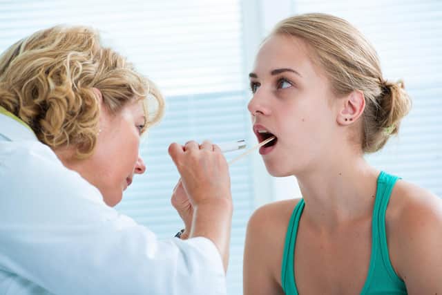 Doctor checking with depressor sore throat to teenage girl. Picture: Adobe Stock.