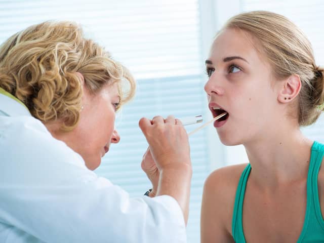 Doctor checking with depressor sore throat to teenage girl. Picture: Adobe Stock.