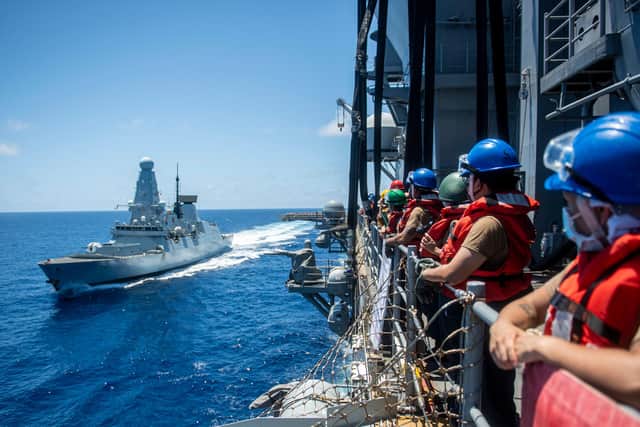 American Sailors assigned to the forward-deployed amphibious assault ship USS America, man the rails before a fueling-at-sea with Royal Navy destroyer HMS Defender. Photo:  US Navy.