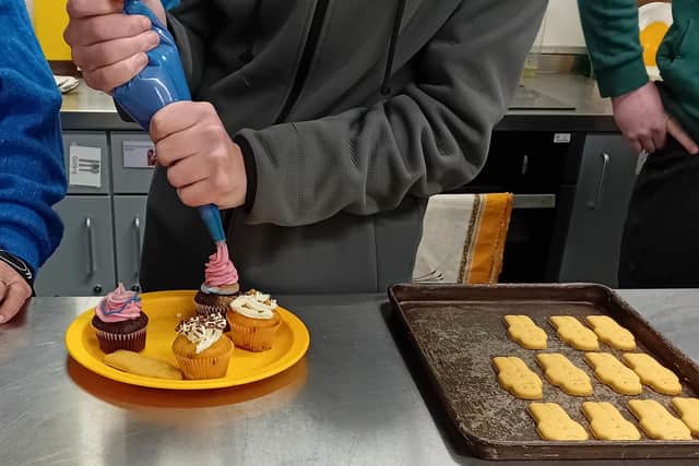 A Harbour School student concentrates on piping icing during a cake decorating session with the Royal Maritime Hotel team.