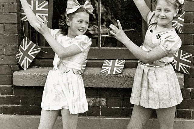 Festival of Britain street tea outside 14, Moorland Road, Buckland Portsmouth. Kay Britno, aged 9, (on left) and friend from Madame Selwood's dance troop 
outside her grandparent’s house entertaining the neighbours at a Festival of Britain street party in 1951