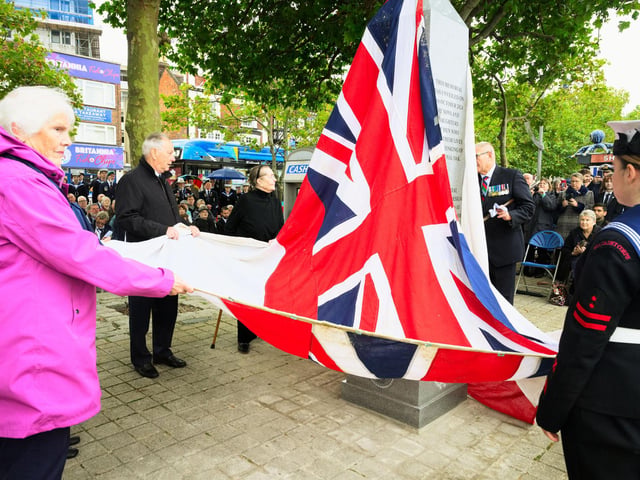 Pictured is: Sons and daughters of the men and boys who were lost in the sinking of HMS Royal Oak, assisted by Sea Cadets from Portsmouth unveil the memorial using the white ensign that was recovered from the wreck of the ship.